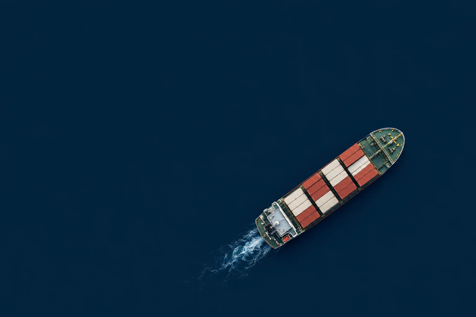A cargo ship crossing a dark navy field beneath a distant horizon
